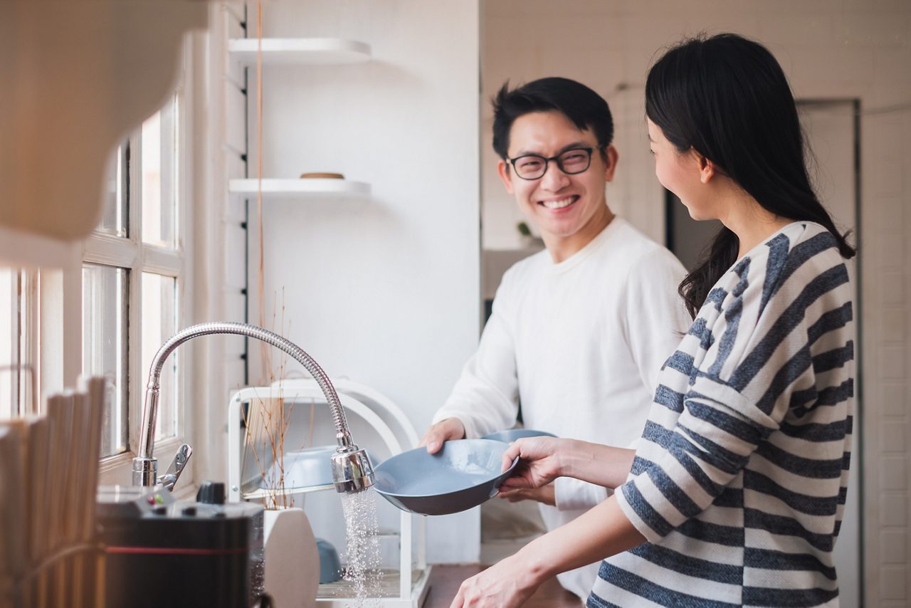 Asian couple family washing dishes together at kitchen.