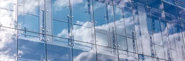 transparent glass wall of modern office building with cloudy sky reflection
