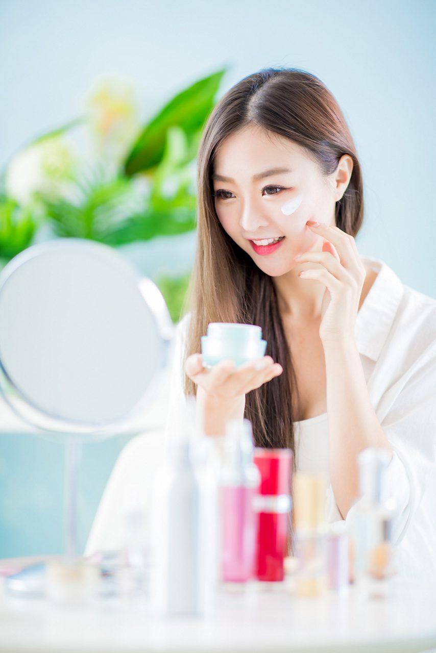 美容アジア人女性が自宅で顔にローションを塗る