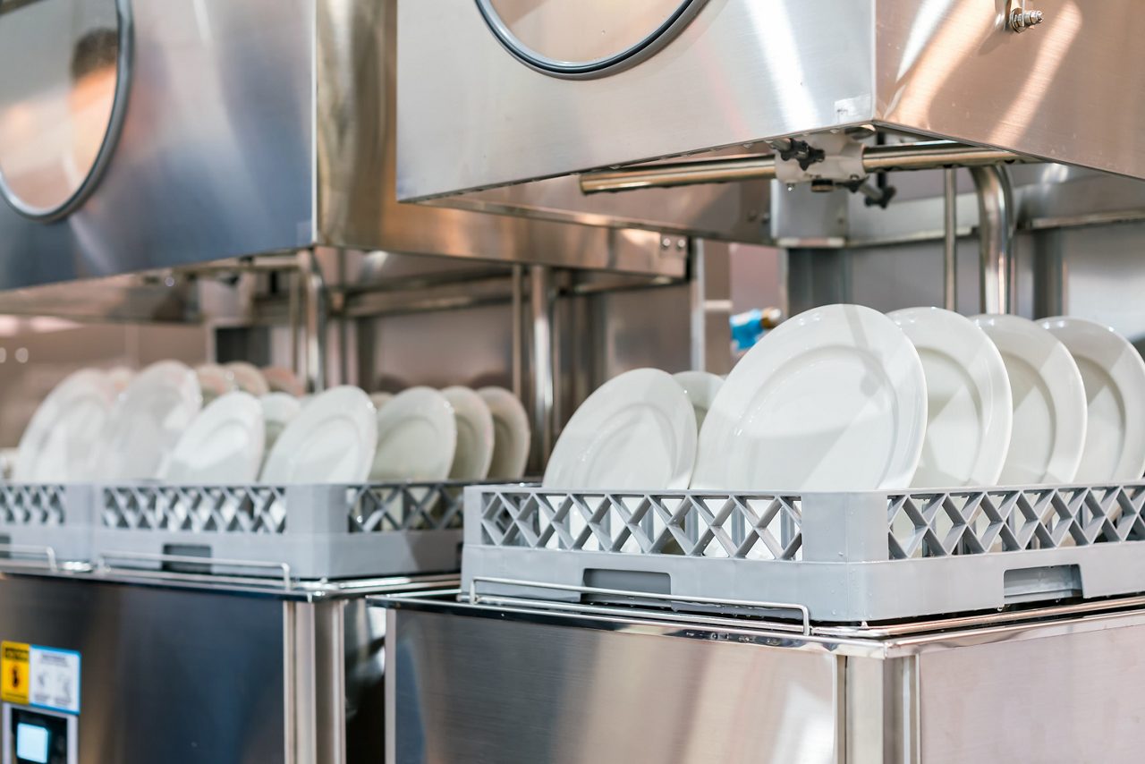 Lava-louças industrial cheia de pratos brancos limpos e secos