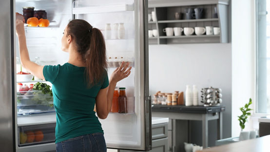 Woman taking food out of fridge at home