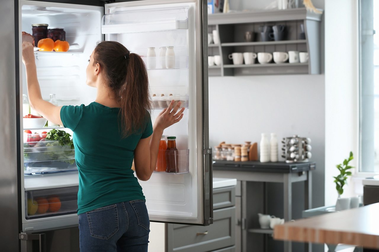 Woman taking food out of fridge at home