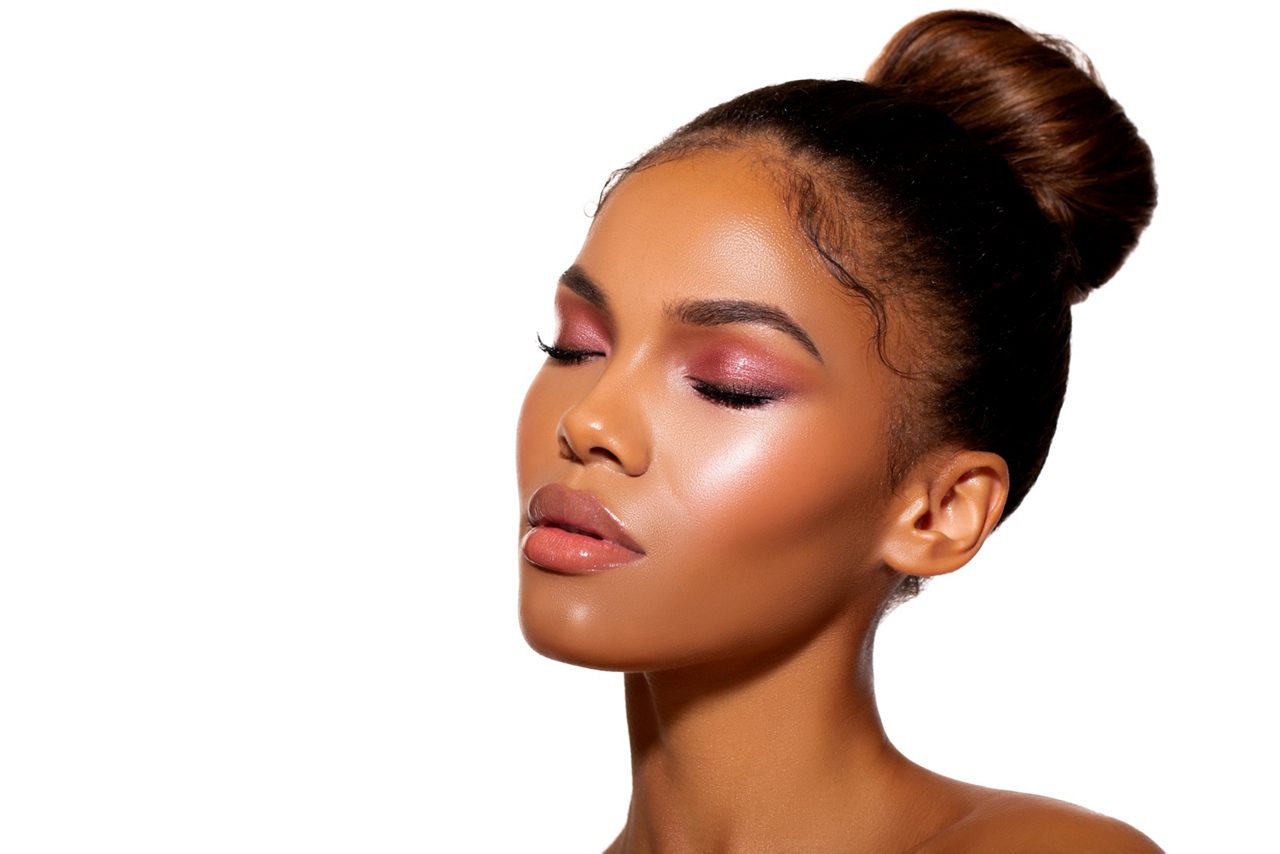 Black woman with eyes closed wearing her hair in a high bun