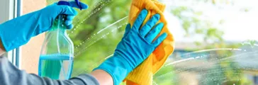 Person cleaning windowpane with detergent 