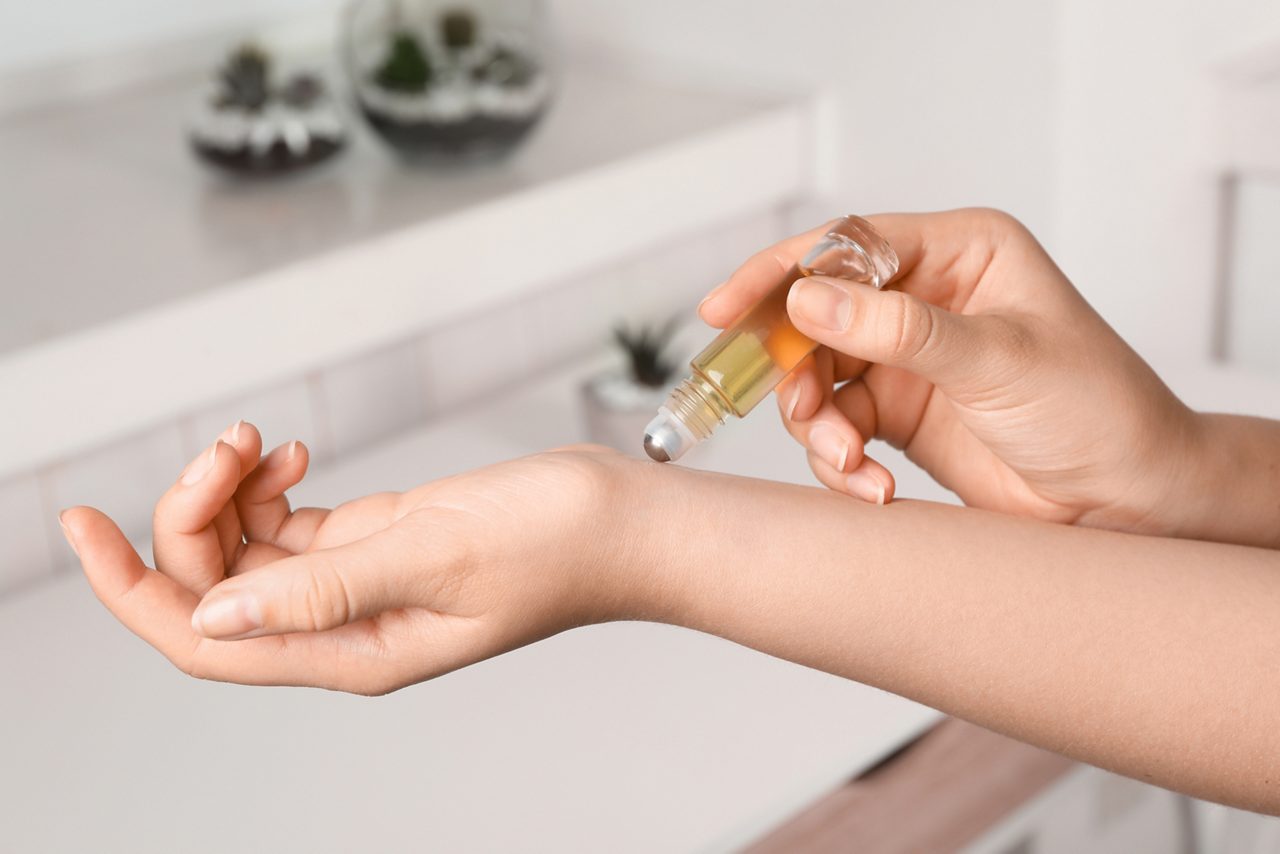 Woman applies rollerball perfume on wrist