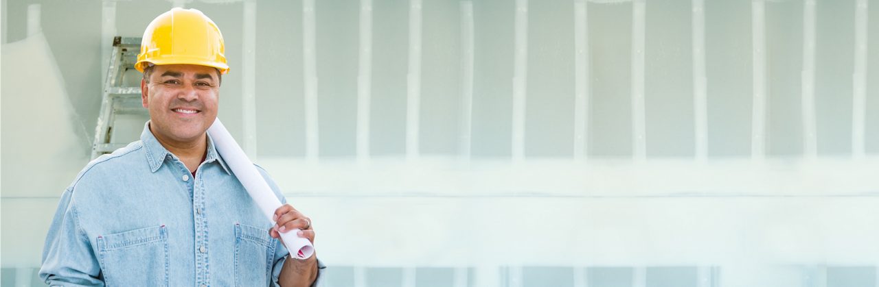 Man in hard hat smiling with roll of paper