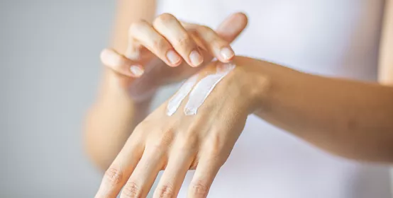 Young woman applying hand cream to care and protect skin
