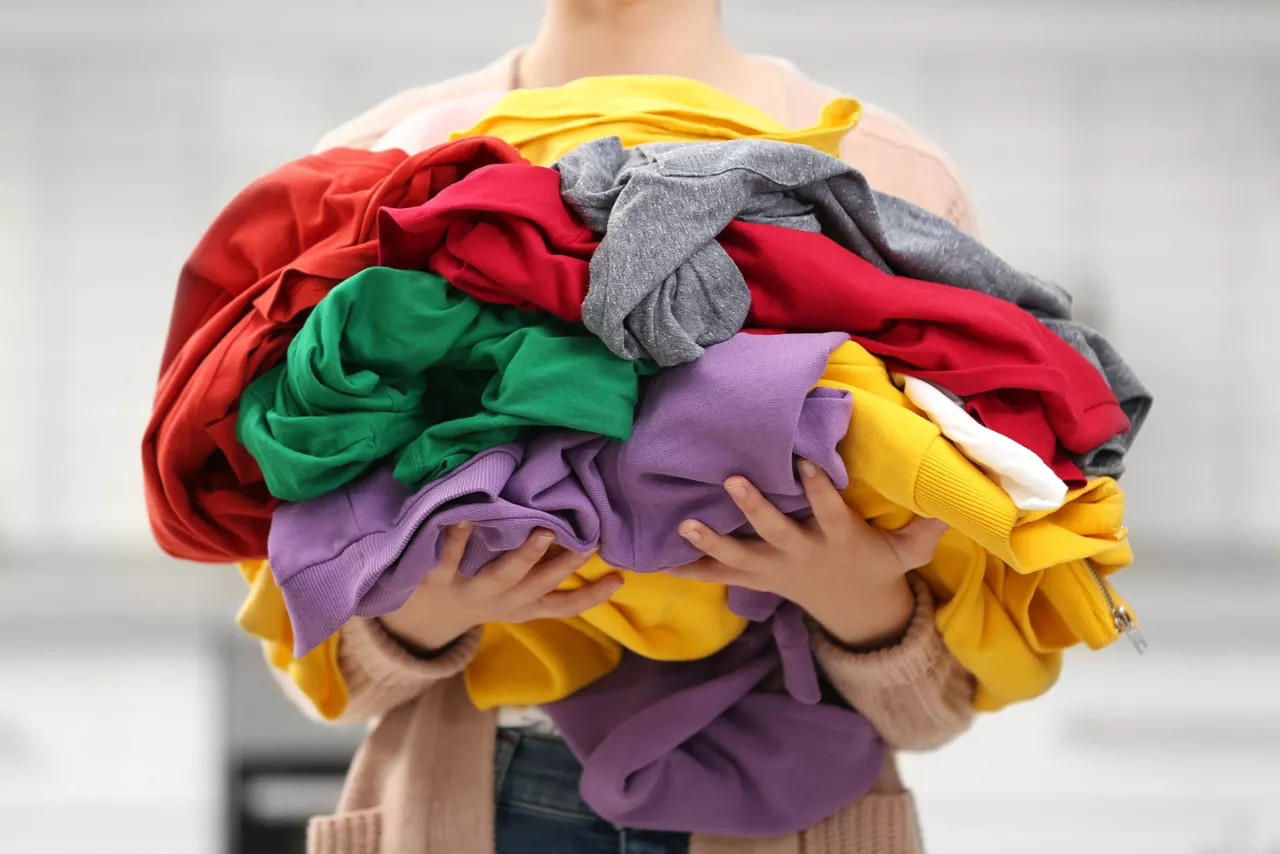 Woman holding pile of dirty laundry indoors, closeup