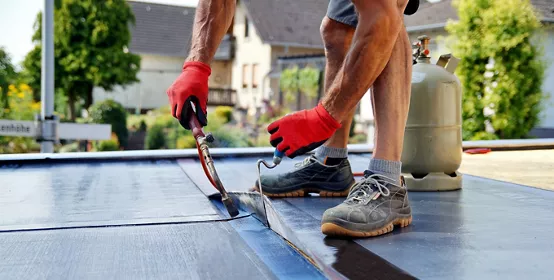 Flat roof installation with propane blowtorch during construction works with roofing felt. Heating and melting bitumen roofing felt. Roofing felt. Roofer working. Roofer working tool. Waterproofing