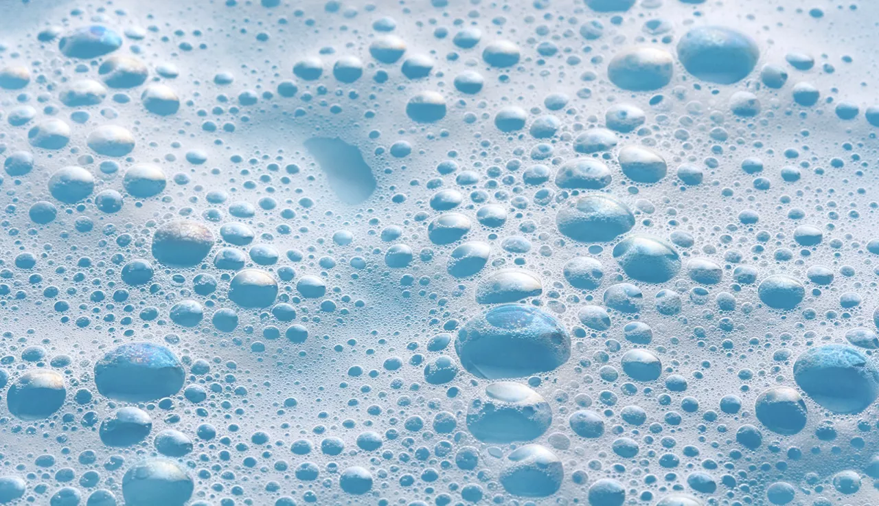 Soap foam on blue background, bubbles macro