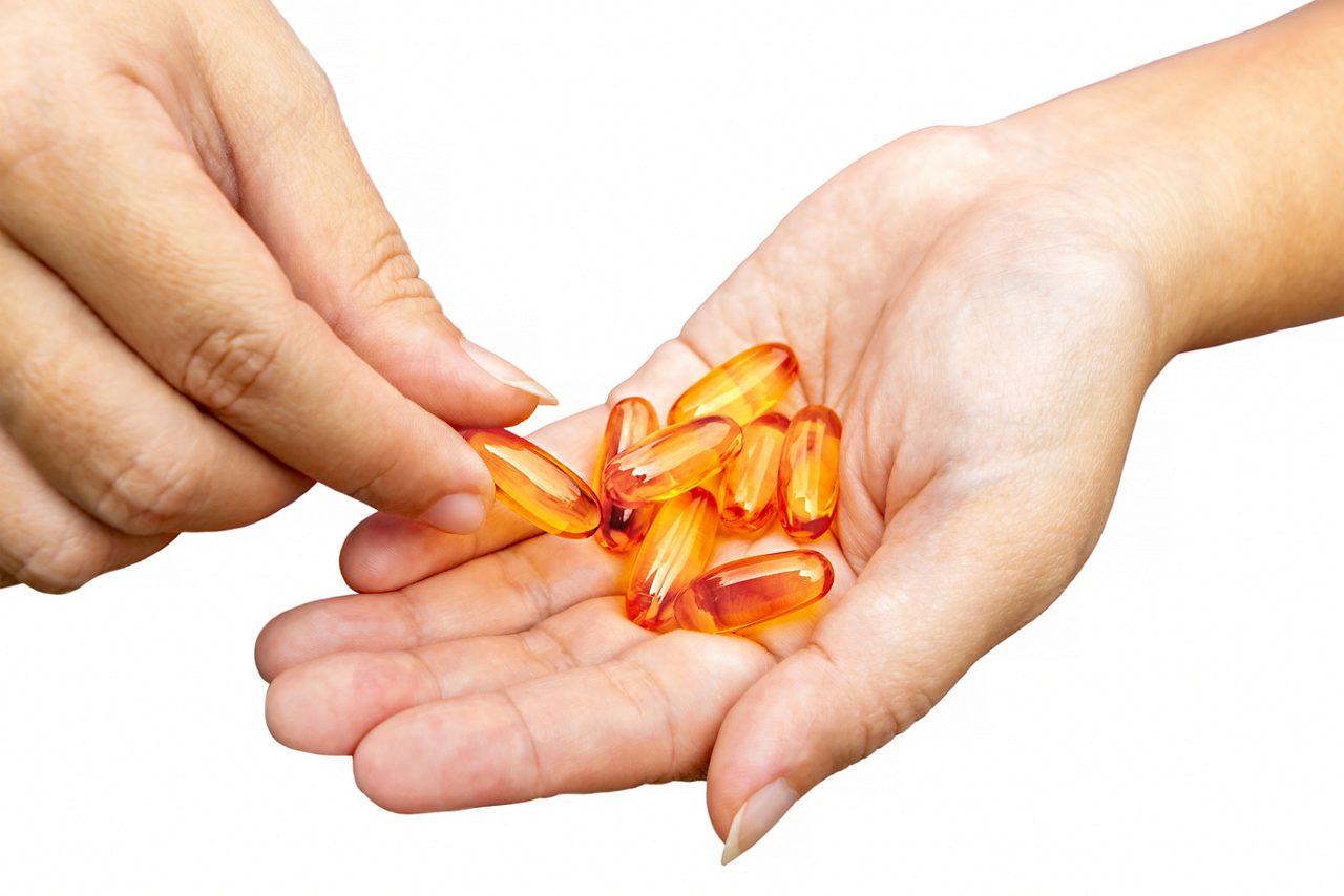 Person holding capsules in hand on white background