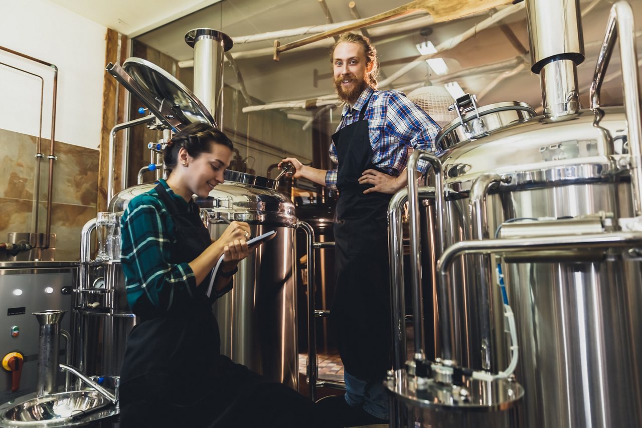 Fábrica de cerveja com funcionários trabalhando ao seu redor.