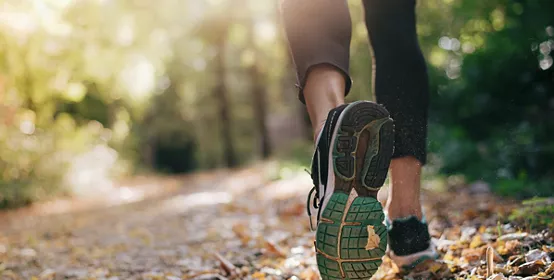 Closeup of running shoe of the person running in the nature with beautiful sunlight.