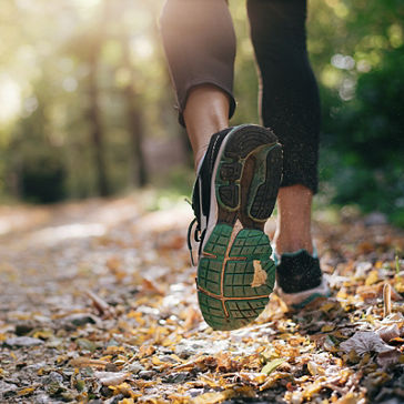 Closeup of running shoe of person running in nature with beautiful sunlight 