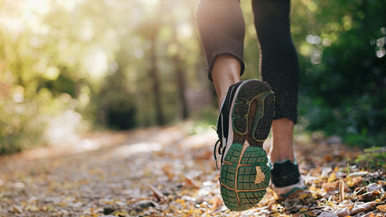 Closeup of running shoe of the person running in the nature with beautiful sunlight 