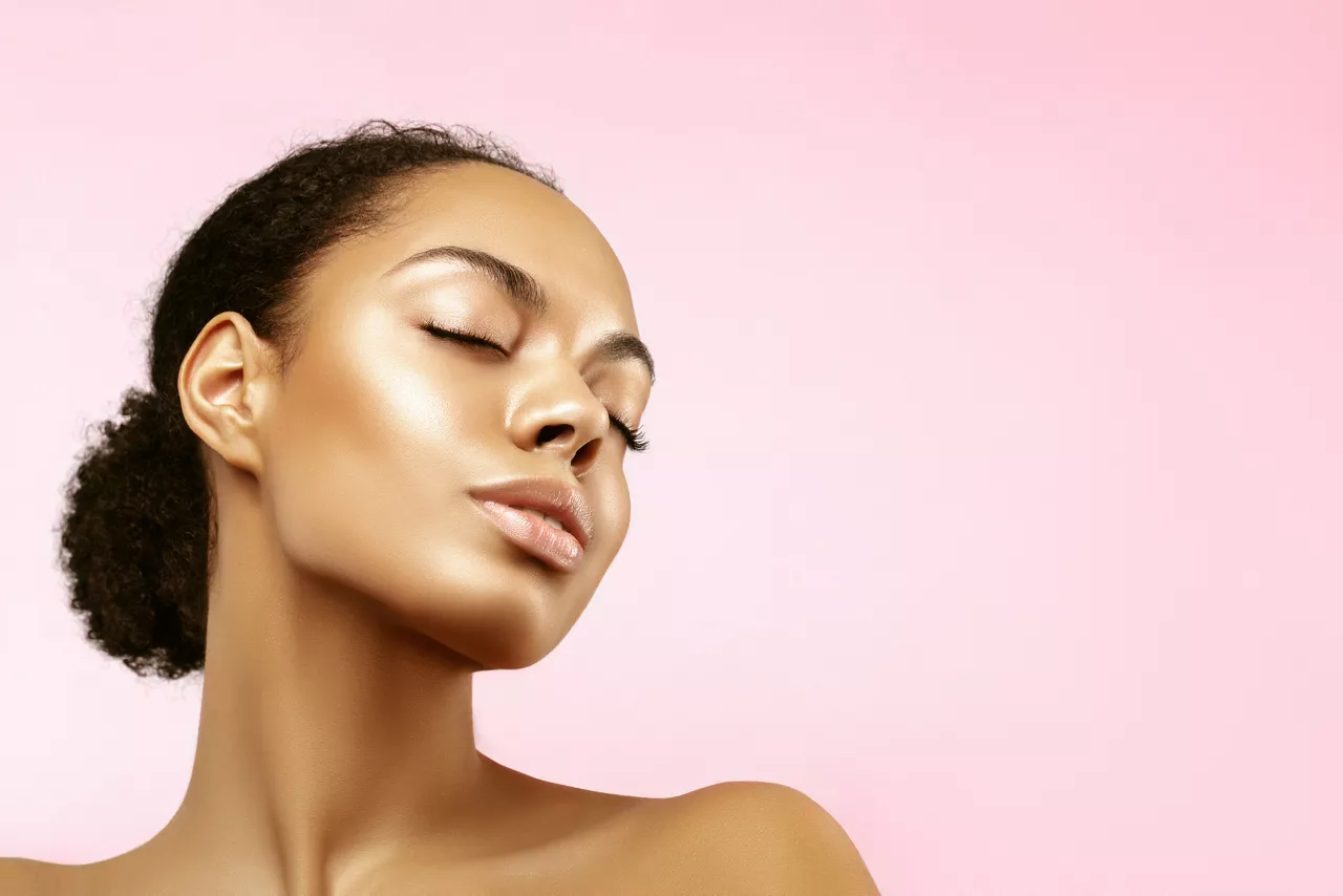 African American skincare models portrait. Beauty spa treatment concept.Young girl posing with closed eyes against pink background