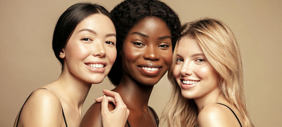Beauty. Multi Ethnic Group of Women with different types of skin  together and looking on camera. Diverse ethnicity women - Caucasian, African and Asian posing and smiling against beige background.