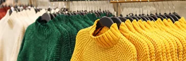 Colored sweaters hanging on a hangers in store women's clothing close-up