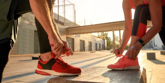 Active morning. Close up photo of two people in sport clothes tying shoelaces before running together outdoors. Fit, fitness, exercise. Healthy lifestyle concept