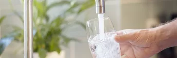 Filling up a glass with clean drinking water from kitchen faucet