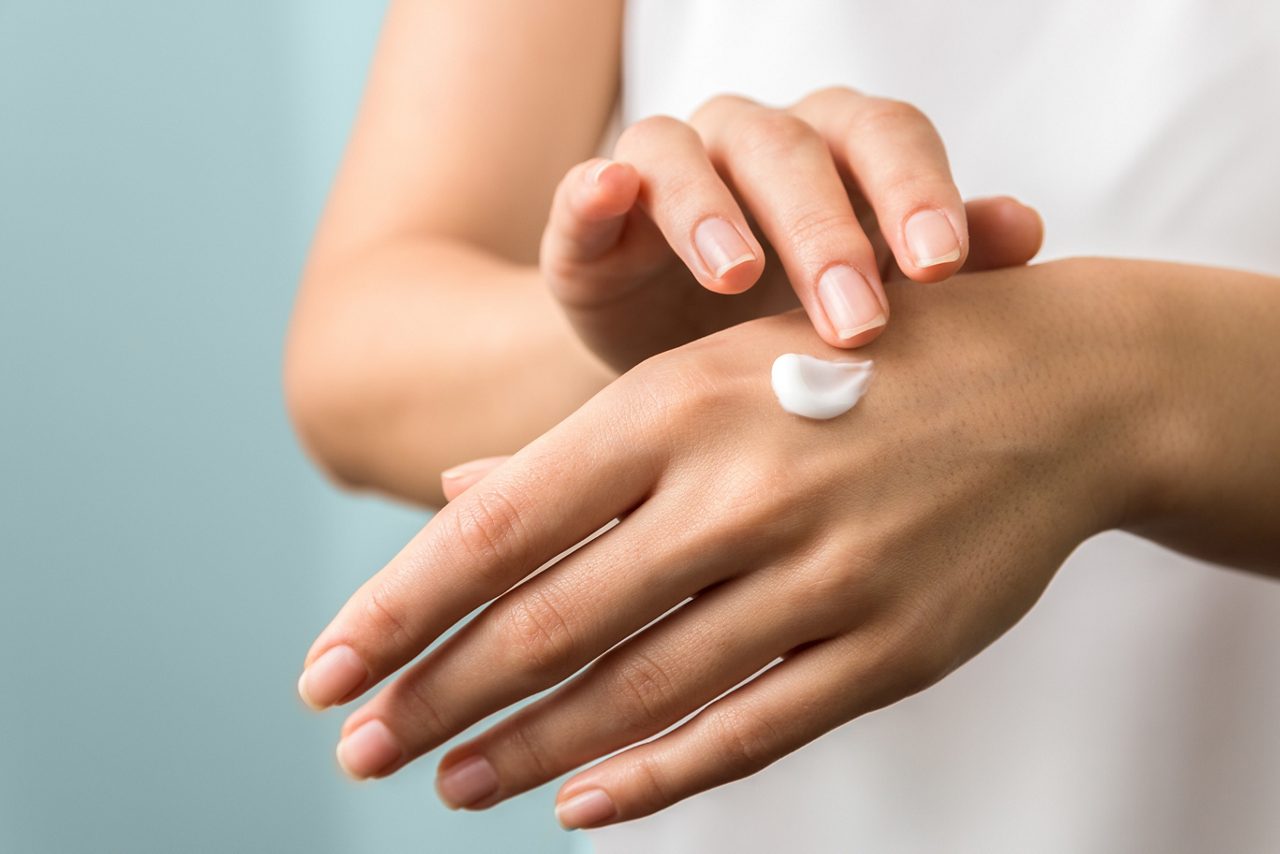 Healthy hands and nails showing seasonal skin protection with woman applying moisturizer on hands