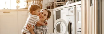Happy mother and son in laundry with washing machine