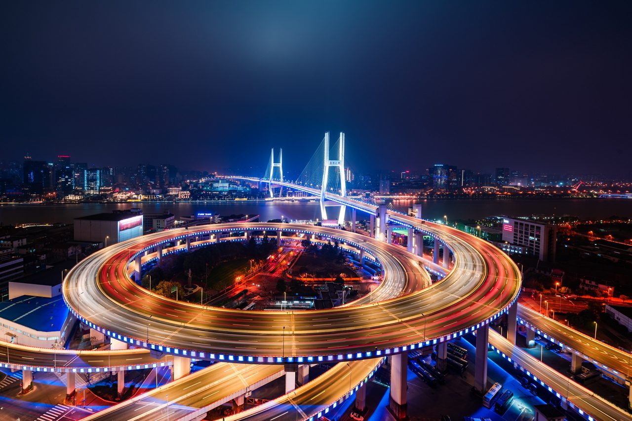 Paisagem urbana noturna com ponte iluminada e viaduto