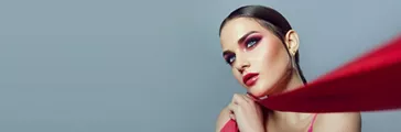 Portrait of a beautiful young woman with bright red make-up and red ribbons in her hands