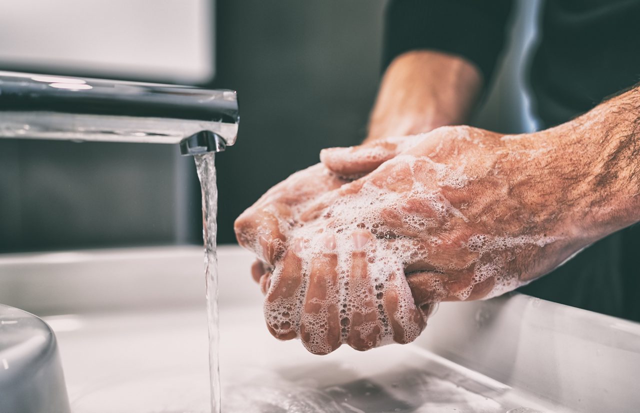 Man washing hands in bathroom sink