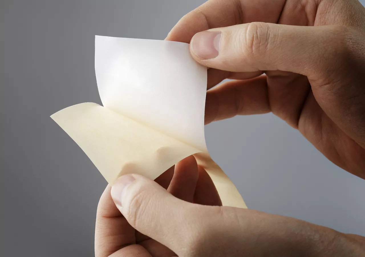 Peeling away a sticker from its backing paper or release paper