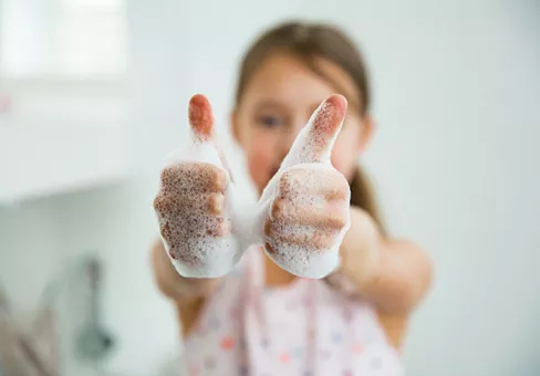 Child washing hands and giving thumbs up