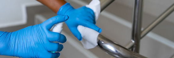 Closeup of female hand using wet wipe and hand sanitizer spray to clean stainless steel staircase railing. Antiseptic, disinfection, cleanliness and healthcare, antivirus concept. Antibacterial.