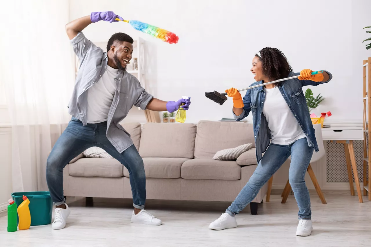 Couple joke fighting with cleaning tools