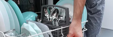 A man puts the tablet in the dishwasher to wash dirty dishes