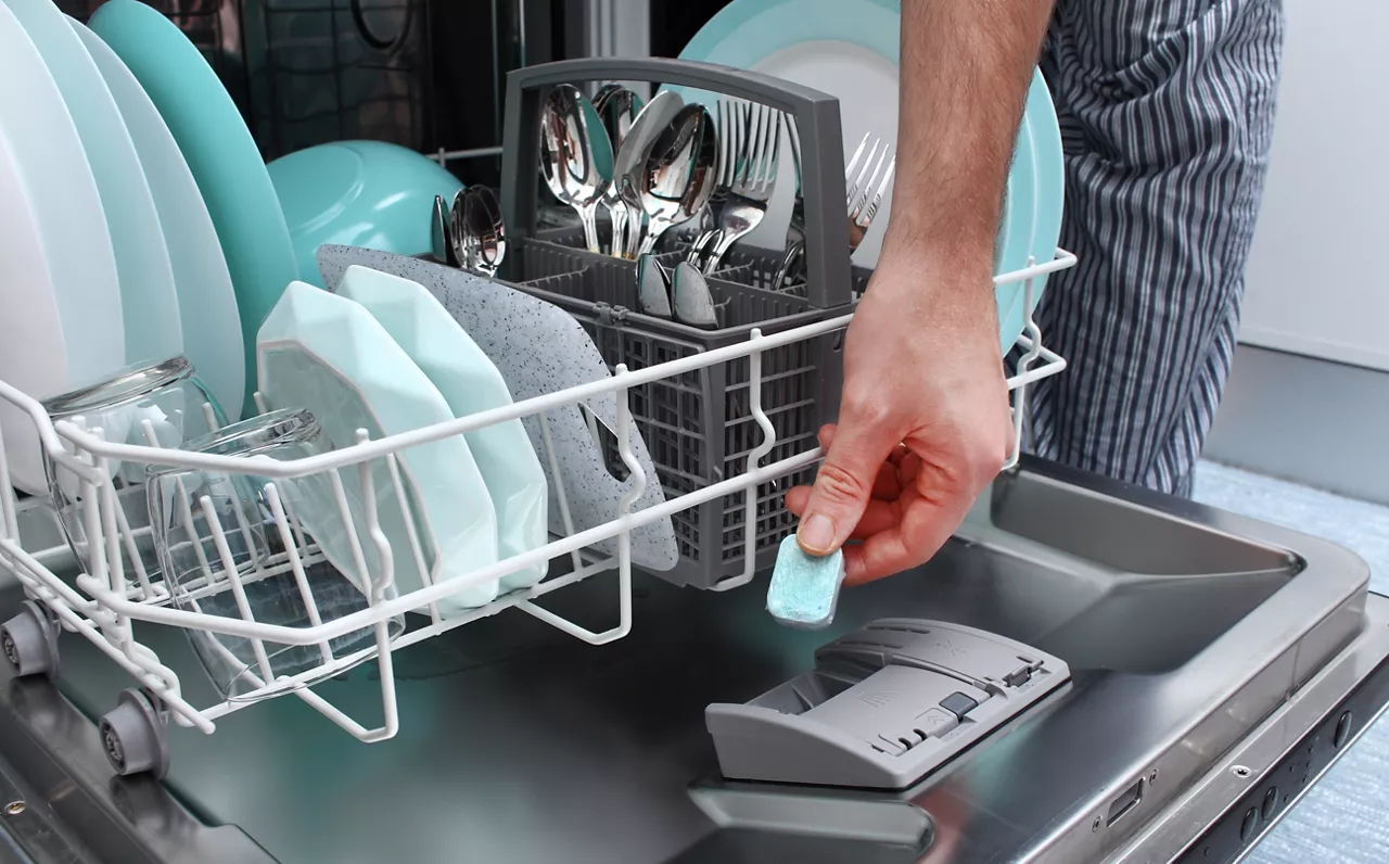 A man puts the tablet in the dishwasher to wash dirty dishes