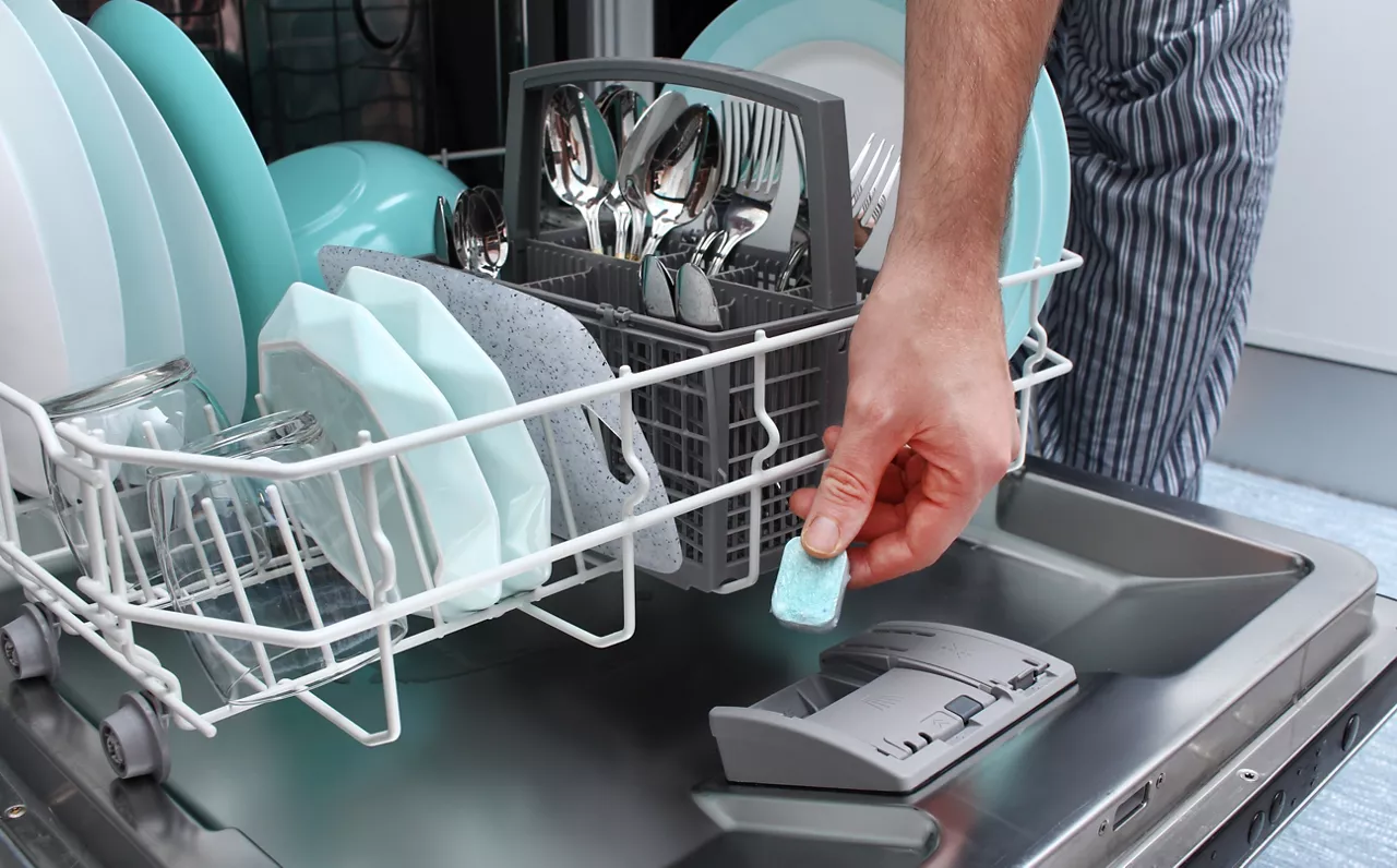 Dishwasher detergent being placed into dishwasher 