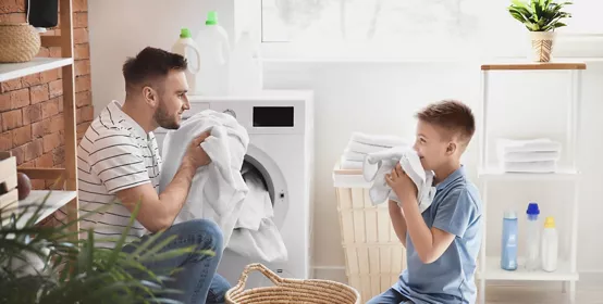 Man and his little son doing laundry at home