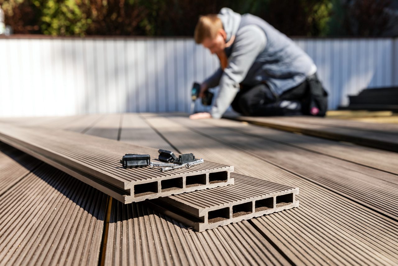 wpc terrace construction - worker installing wood plastic composite decking boards