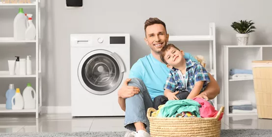 Man and his little son doing laundry at home