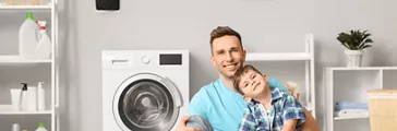 Man and his little son doing laundry at home