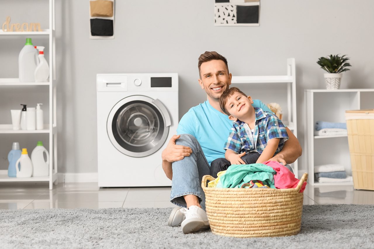 Father and son sitting on the floor doing laundry