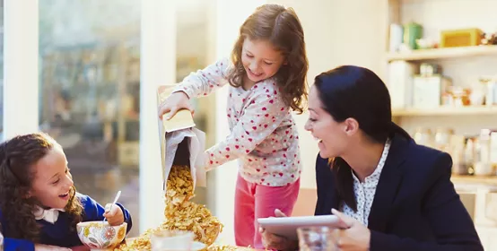 Girl pouring abundance of cereal at breakfast table