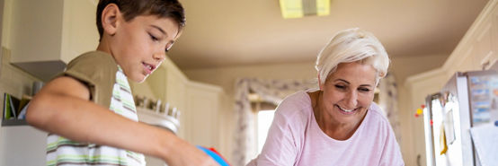 Neto e avó limpando a mesa da cozinha com spray