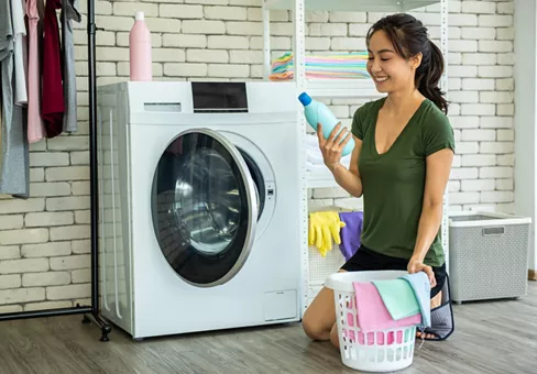 Washing Machine; Young woman doing laundry at home.