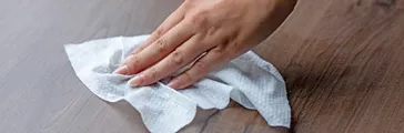 Woman's hand cleaning home office table surface with wet wipes