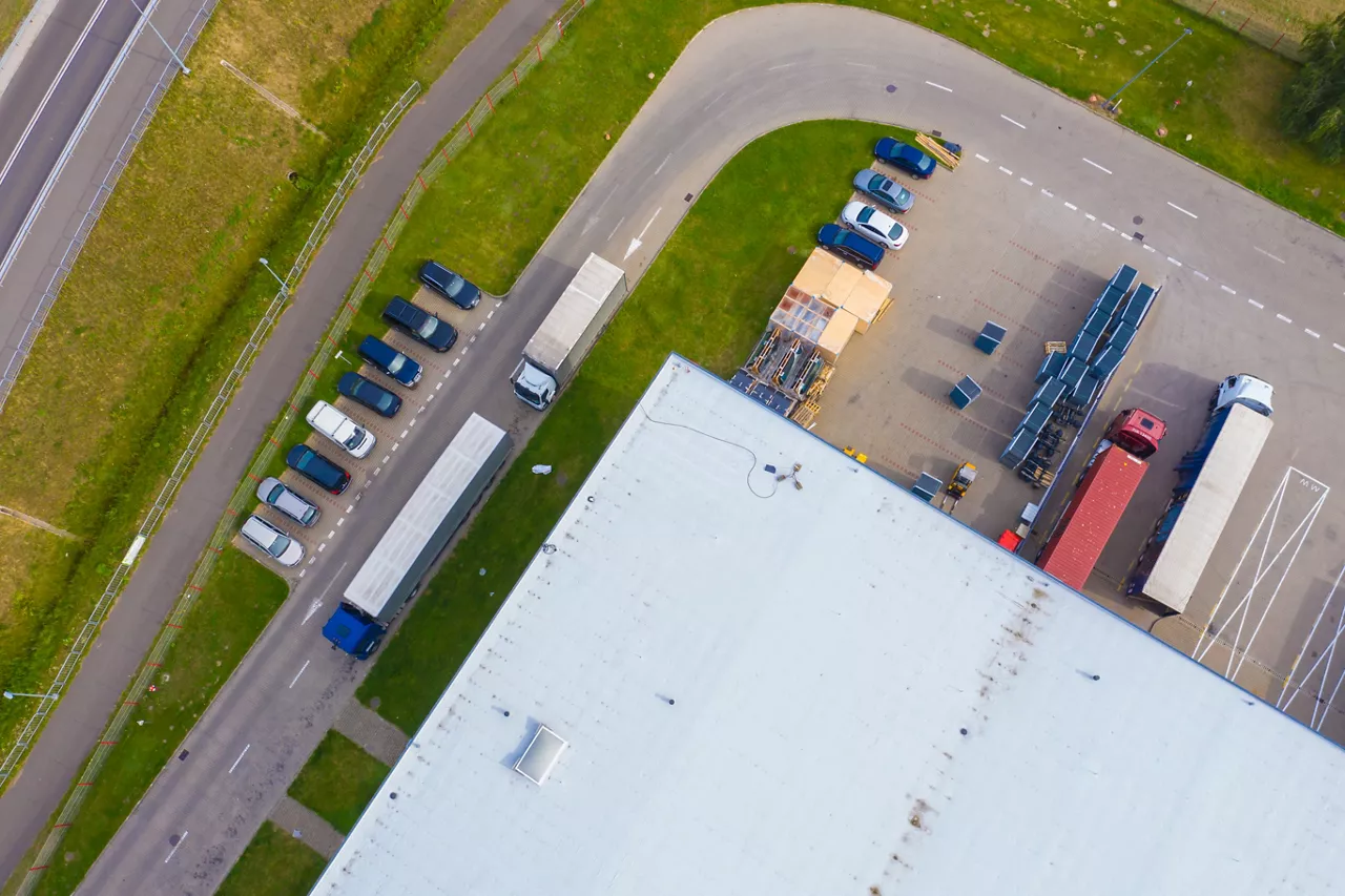 Aerial drone view of group of large modern industrial warehouse or factory buildings in suburban city area. Logistic transportation cargo terminal.