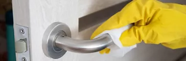 Woman hand wiping doorknob with antibacterial disinfecting wipe