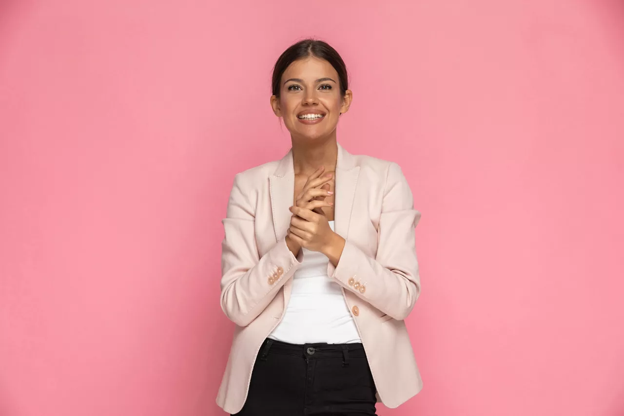 young beautiful businesswoman holding her hand and smiling at the camera on pink background