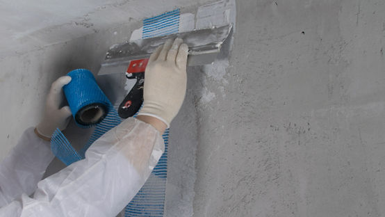 wallboard being spread across grey wall