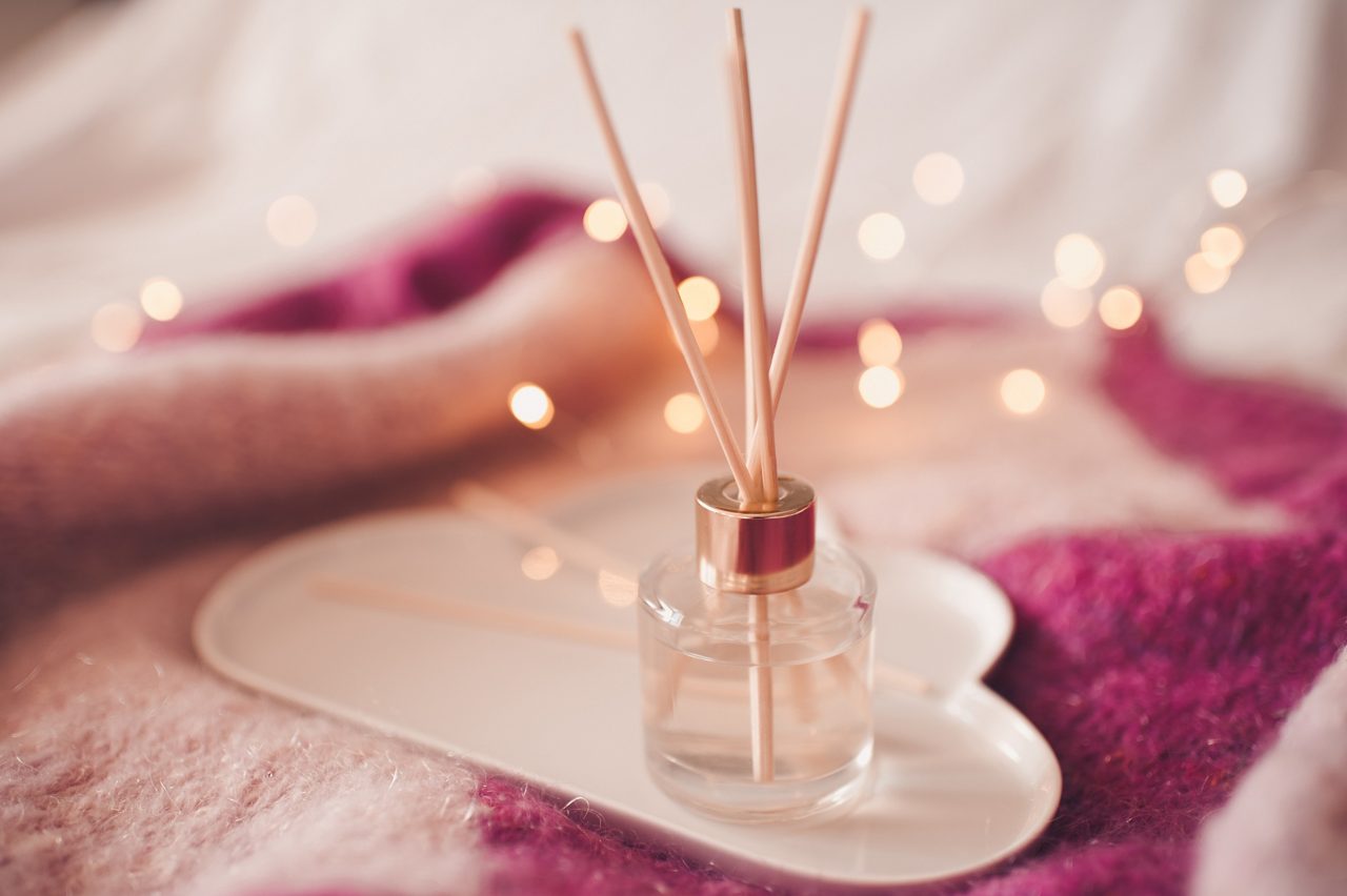 Liquid home fragrance with aroma sticks in glass bottle closeup. Home refreshment.